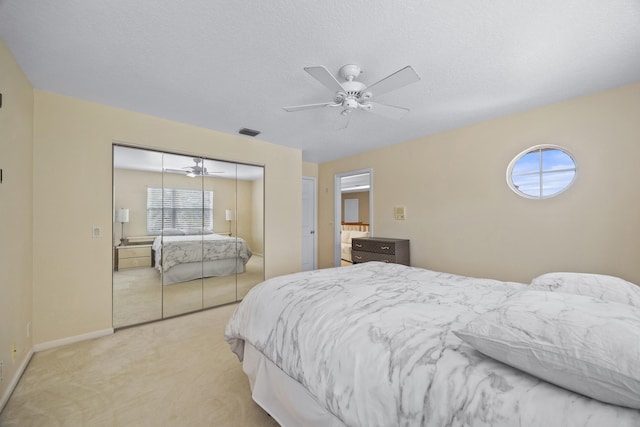 carpeted bedroom with ceiling fan, a closet, and a textured ceiling