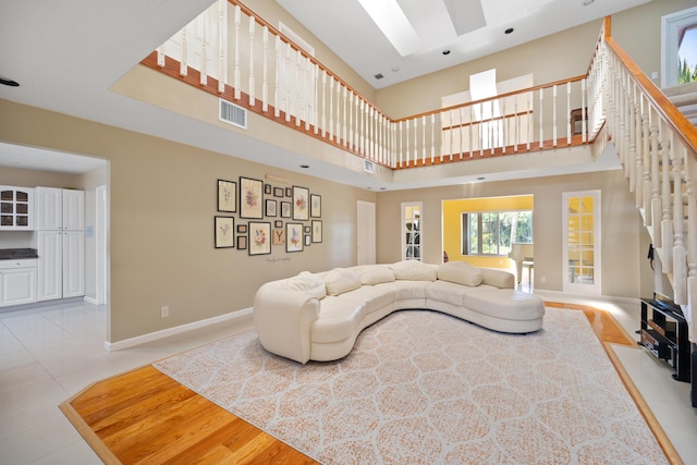 tiled living room with a towering ceiling and a skylight