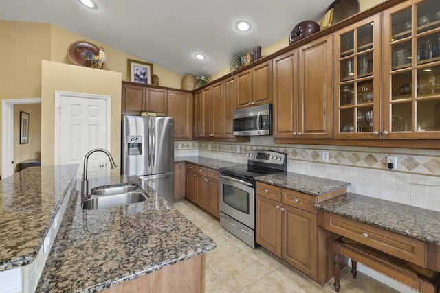 kitchen with backsplash, stainless steel appliances, dark stone countertops, and sink