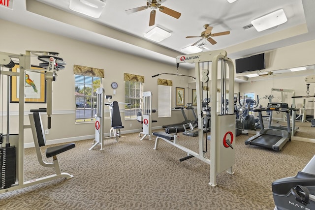 workout area with carpet floors, a raised ceiling, and ceiling fan