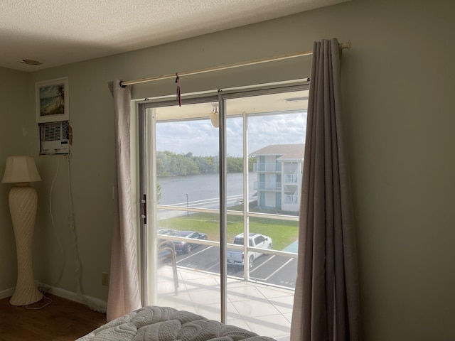 entryway with a water view, an AC wall unit, a textured ceiling, and light hardwood / wood-style floors