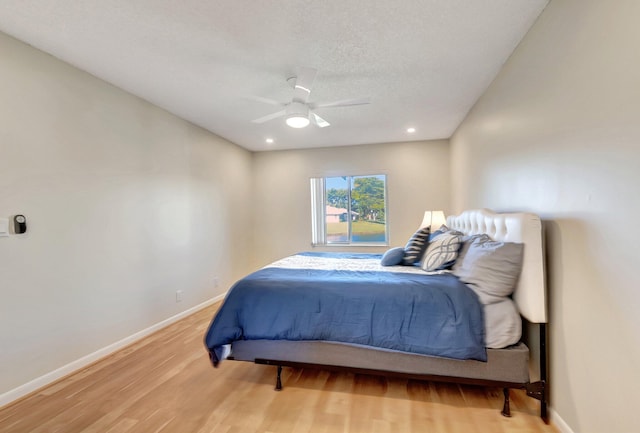 bedroom with wood-type flooring, a textured ceiling, and ceiling fan