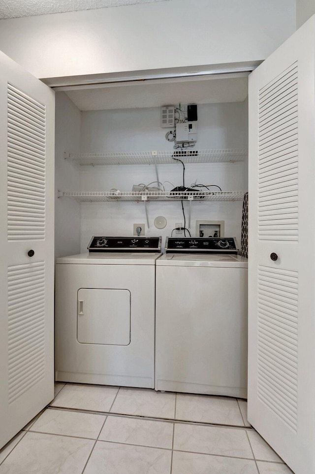 laundry room with light tile patterned flooring and washing machine and clothes dryer