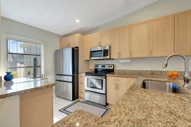 kitchen featuring light stone countertops, a textured ceiling, stainless steel appliances, sink, and light brown cabinets