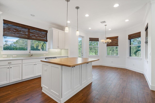 kitchen featuring sink, butcher block countertops, dark hardwood / wood-style floors, a kitchen island, and white cabinets