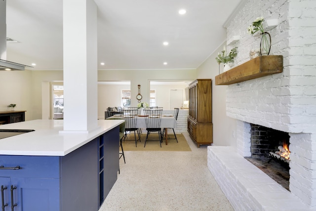 kitchen with a brick fireplace, blue cabinetry, and a kitchen breakfast bar