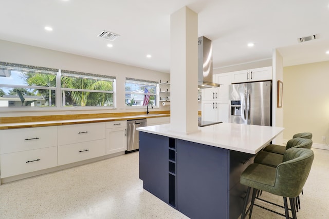 kitchen featuring appliances with stainless steel finishes, a center island, white cabinets, and ventilation hood