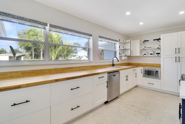 kitchen with appliances with stainless steel finishes, wooden counters, white cabinets, and sink