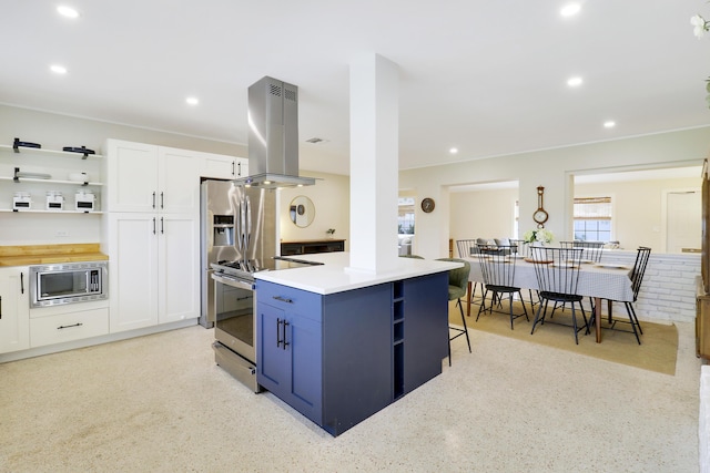 kitchen with island range hood, a center island, a breakfast bar area, appliances with stainless steel finishes, and white cabinetry