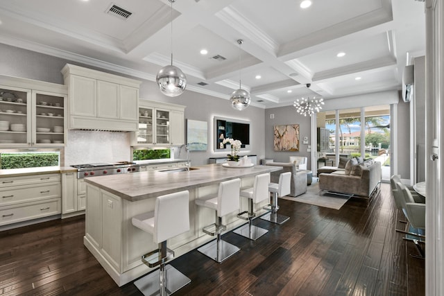 kitchen with a breakfast bar, sink, a kitchen island with sink, stainless steel gas cooktop, and light stone countertops