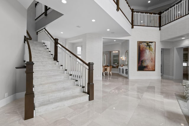 stairs with crown molding and a towering ceiling