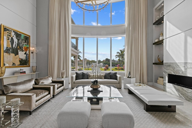 living room featuring a notable chandelier, a fireplace, and a high ceiling