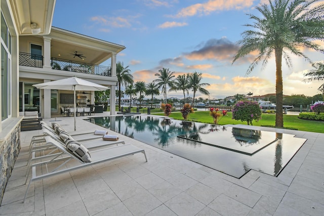 13791 Baycliff Dr, Juno Beach, FL 33408 - pool at dusk with a patio area, ceiling fan, an infinity pool, and a yard