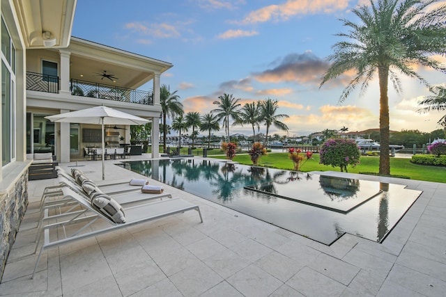 pool at dusk featuring a patio