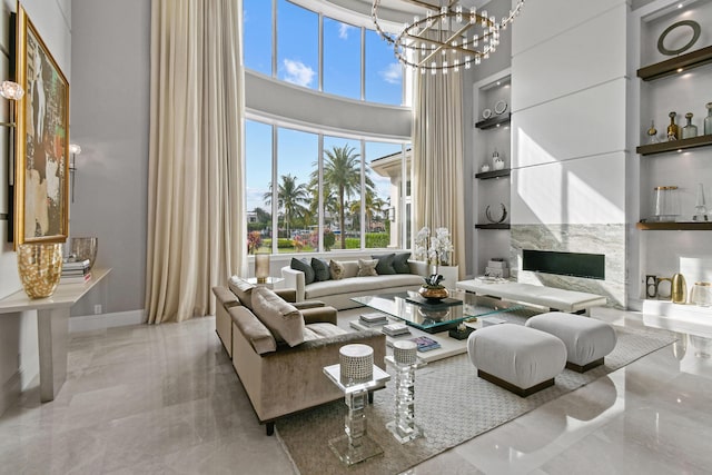 living room with an inviting chandelier, a towering ceiling, and a premium fireplace