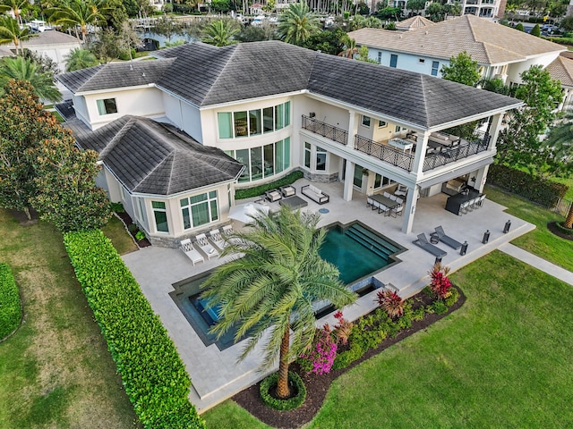 back of house featuring a balcony, an outdoor hangout area, a patio area, and a lawn