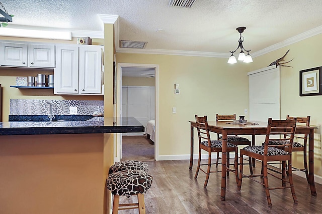 dining area featuring hardwood / wood-style flooring, an inviting chandelier, a textured ceiling, and ornamental molding