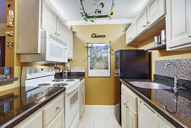 kitchen with white cabinetry, white appliances, a textured ceiling, and light tile patterned floors