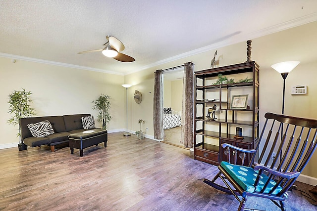 living area with hardwood / wood-style floors, a textured ceiling, ceiling fan, and ornamental molding