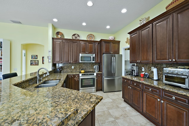 kitchen featuring backsplash, dark stone countertops, sink, and stainless steel appliances