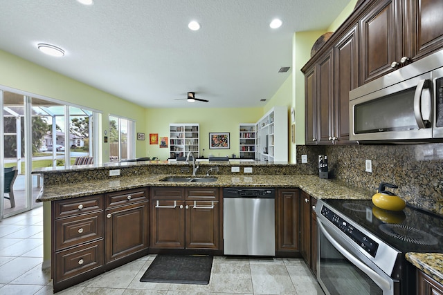 kitchen featuring sink, kitchen peninsula, stainless steel appliances, and dark stone counters