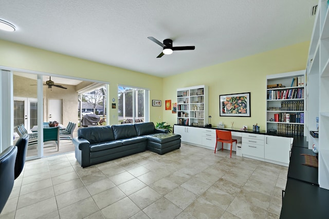 living room with ceiling fan, built in features, light tile patterned floors, and a textured ceiling