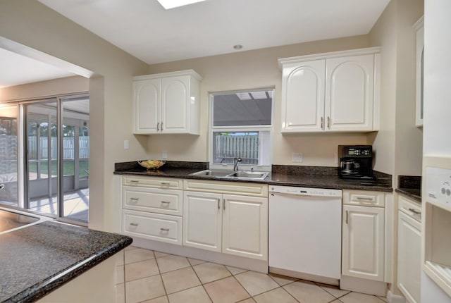 kitchen with dishwasher, light tile patterned floors, white cabinetry, dark stone counters, and sink