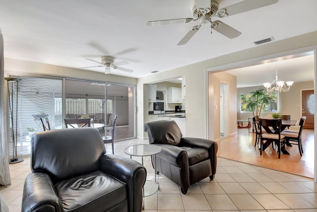 tiled living room featuring ceiling fan with notable chandelier