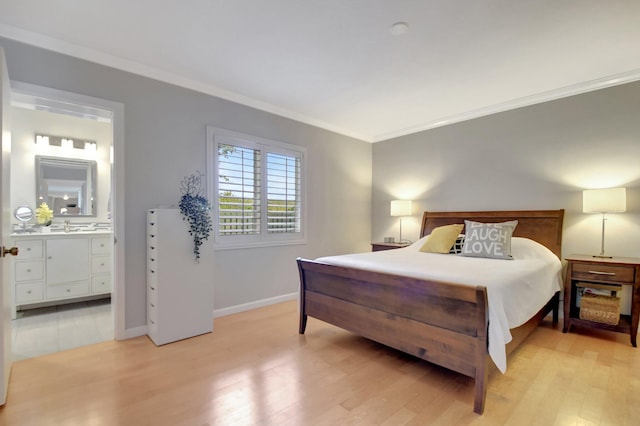 bedroom with ornamental molding, light hardwood / wood-style floors, ensuite bath, and sink