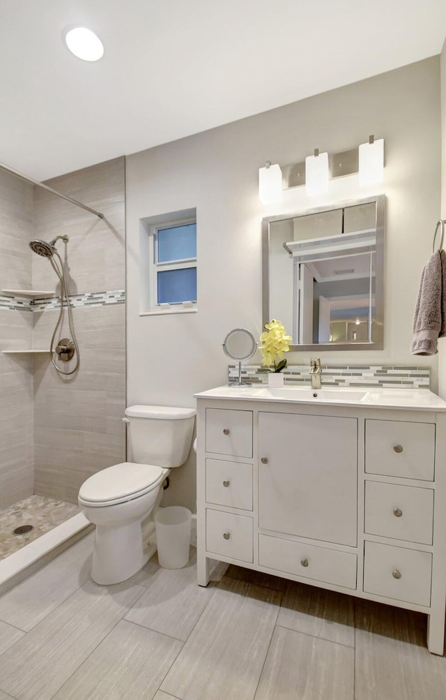 bathroom with tiled shower, vanity, and toilet