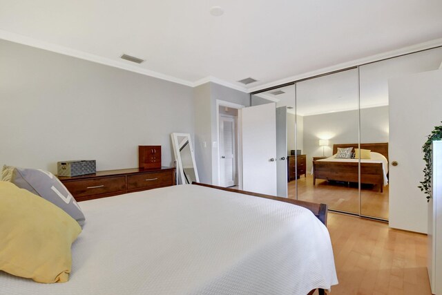 bedroom featuring ornamental molding, a closet, and light hardwood / wood-style floors