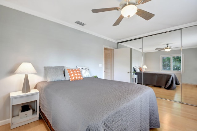 bedroom featuring a closet, ceiling fan, light hardwood / wood-style floors, and crown molding