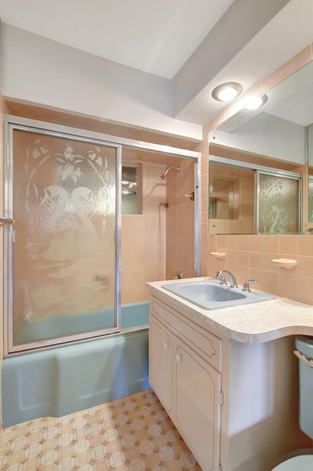 bathroom with vanity, tasteful backsplash, and combined bath / shower with glass door