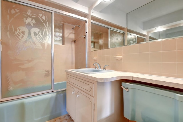 bathroom with vanity, decorative backsplash, and bath / shower combo with glass door