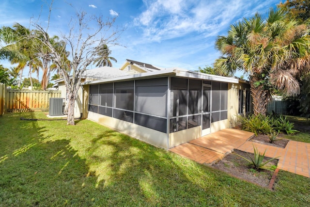 view of home's exterior featuring a patio, central AC, a lawn, and a sunroom