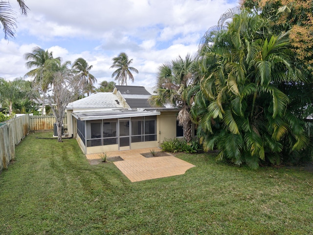 back of property with a patio area, a lawn, and a sunroom