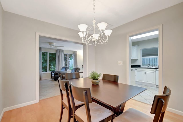 tiled dining space with ceiling fan with notable chandelier and sink