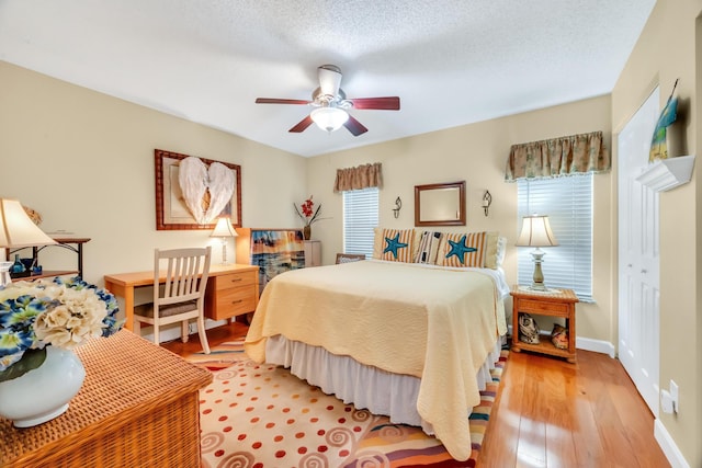 bedroom with multiple windows, a textured ceiling, light hardwood / wood-style flooring, and ceiling fan