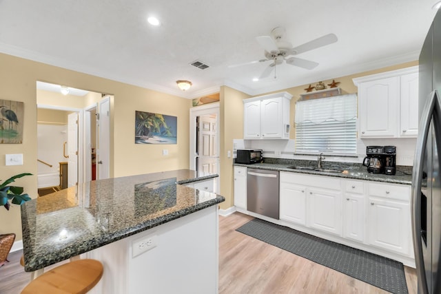 kitchen featuring white cabinets, appliances with stainless steel finishes, dark stone counters, and sink