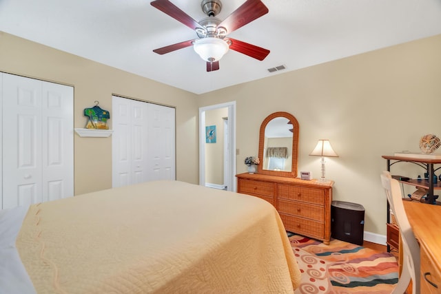 bedroom with ceiling fan and multiple closets