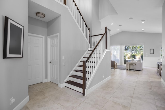 stairs with tile patterned flooring and high vaulted ceiling