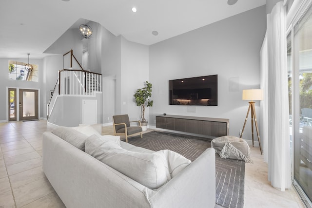 living room featuring french doors, a wealth of natural light, a towering ceiling, and an inviting chandelier