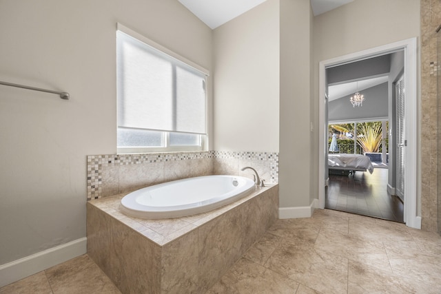 bathroom with a relaxing tiled tub, lofted ceiling, a notable chandelier, and tile patterned flooring