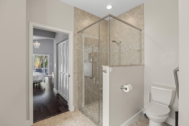 bathroom with a shower with shower door, tile patterned floors, toilet, and an inviting chandelier