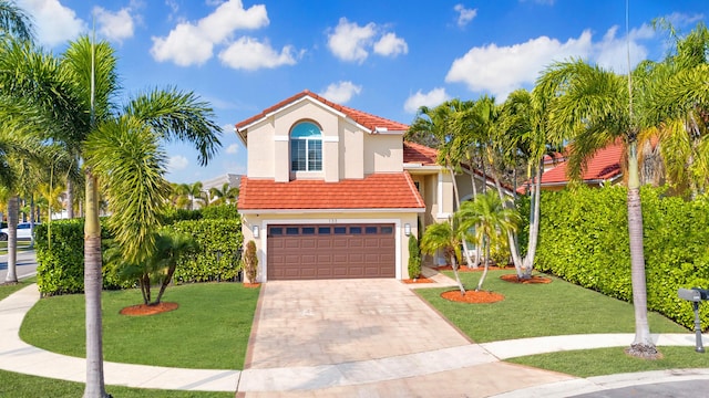 mediterranean / spanish home with a garage and a front lawn