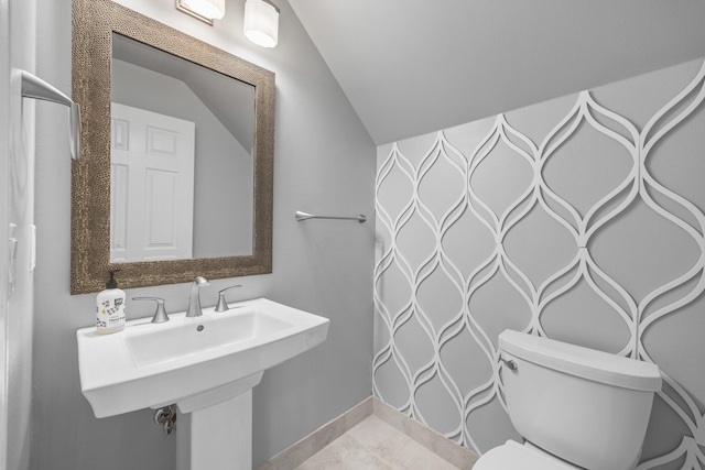 bathroom with vaulted ceiling, toilet, tile patterned floors, and sink