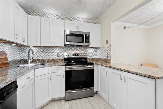 kitchen featuring appliances with stainless steel finishes, a textured ceiling, white cabinetry, and sink