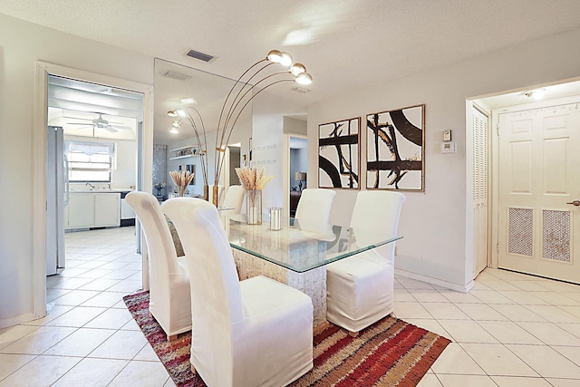 tiled dining room with ceiling fan and a textured ceiling