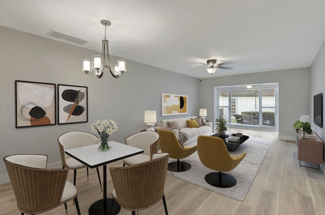 dining space featuring ceiling fan with notable chandelier and light hardwood / wood-style floors