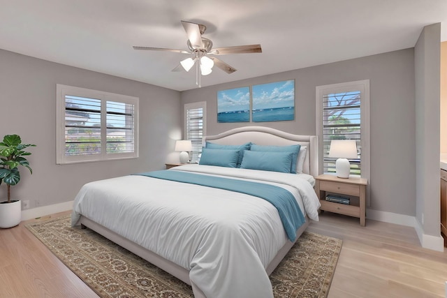 bedroom with ceiling fan, light hardwood / wood-style floors, and multiple windows